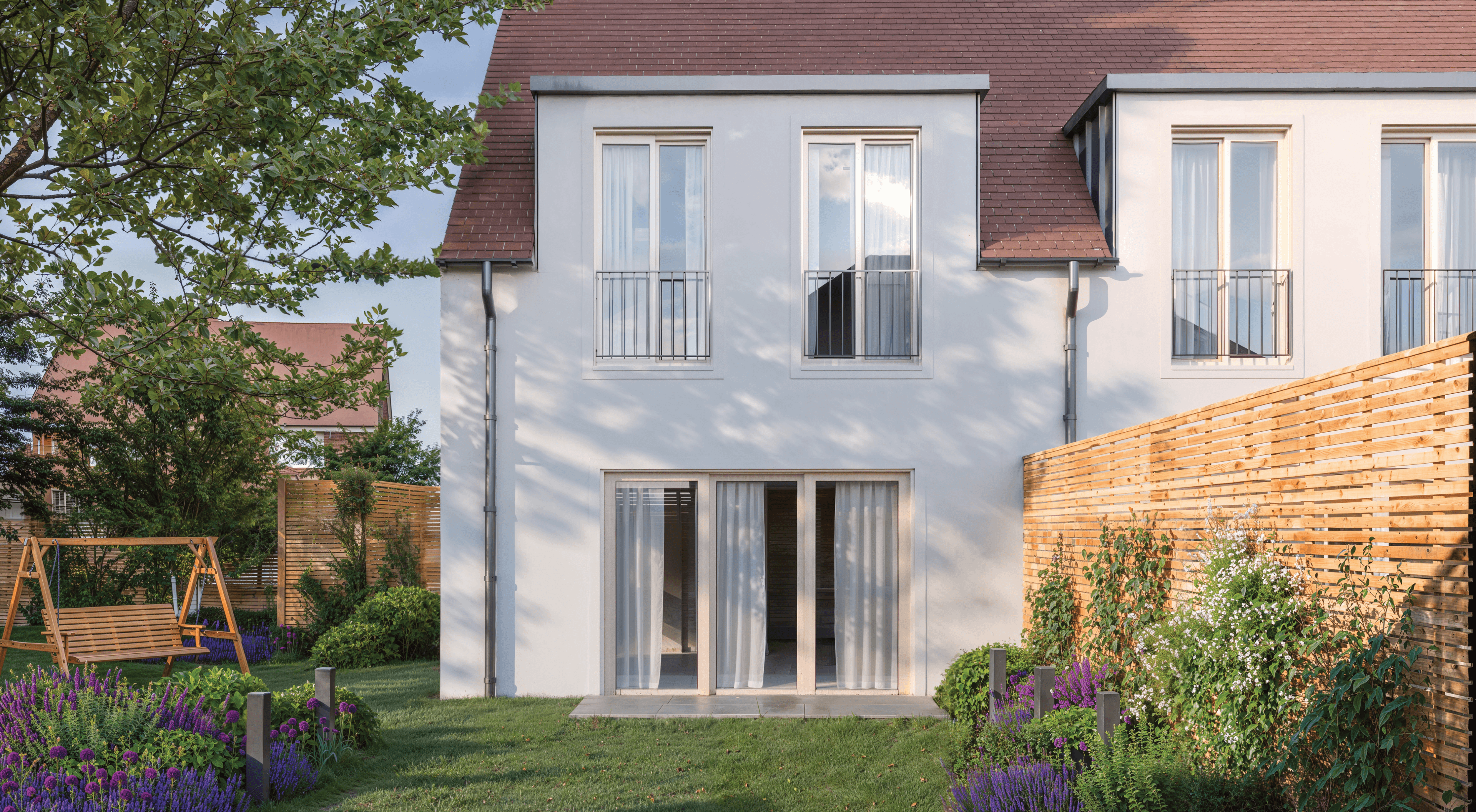 Rear view of the home showing full-width glazing opening onto a private garden space